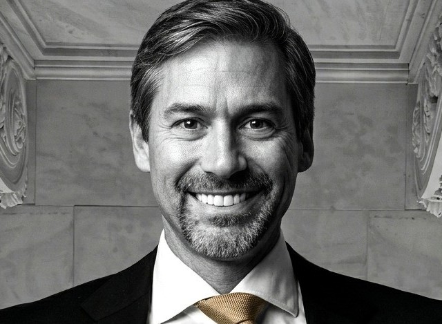 Jared Moss, real estate asset protection attorney in dark suit with gold tie in marble hall